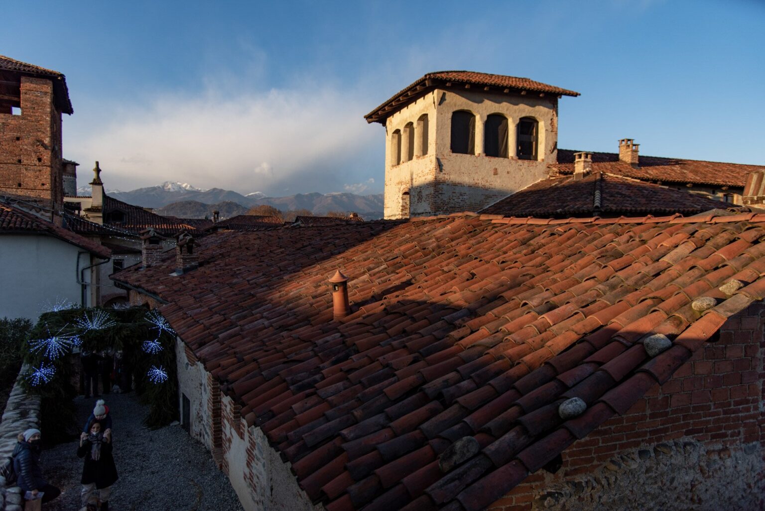Tetti del Ricetto e Casa del Principe al tramonto con le Alpi