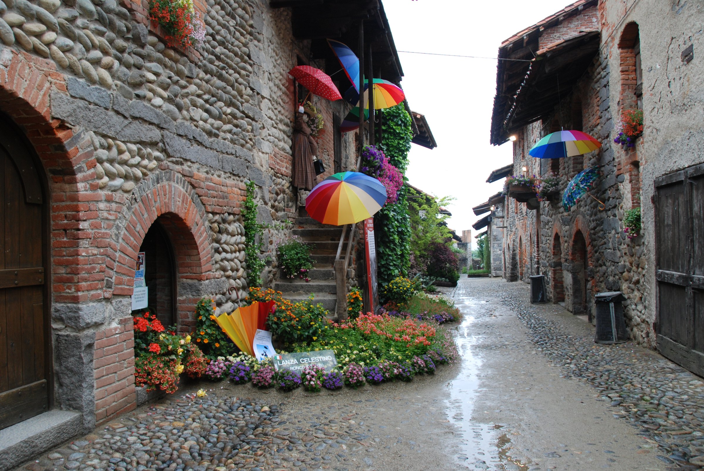 Rua del Ricetto con ombrelli colorati e fiori